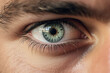 primer plano de un ojo de color azul verdoso y cejas pobladas de un hombre joven