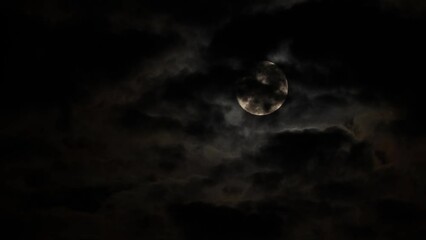Wall Mural - Full Moon in a dark sky on a cloudy night with flying black clouds, like in thrillers and horror films. Real shooting