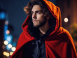 Portrait of Handsome Young Man in Red Cloak on a night city street background. Costume of Wizard, or Magician for Christmas,  New Year or Halloween party