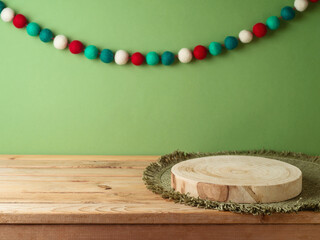 Wall Mural - Empty log board with place mat on wooden table over green wall and garland decoration background. Christmas mock up for design and product display.