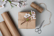 Gift wrapping accessories. Present, craft paper, rope, flowers and scissors on gray background.