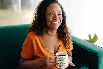 Poster - Morning coffee for retired senior: Woman relaxing on her couch with a hot beverage