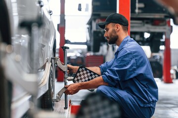 Sitting, checking the tire. Auto mechanic working in garage. Repair service