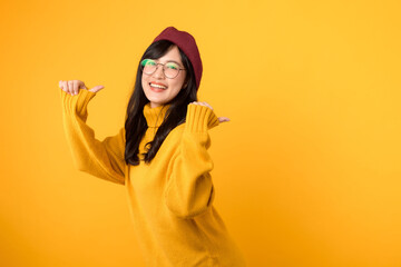 Trust our youth! An attractive woman in a red beret and yellow sweater points her thumb to free copy space with a friendly smile against a vibrant yellow backdrop.