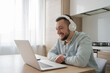 © Julija - Young man with laptop and headphones indoors at home, studying, freelance working