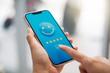 customer satisfaction survey concept businesswoman use smartphone Touch the happy smiley icon. Satisfied. 5 stars. Service experience rating. online application Satisfaction Review best quality.