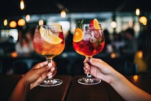 Close Up Of Two Female Hands Holding Glasses Of Cocktails In The Bar, Cropped Image Of Female Friends Clinking Glasses With Cocktails At Bar Counter, AI Generated
