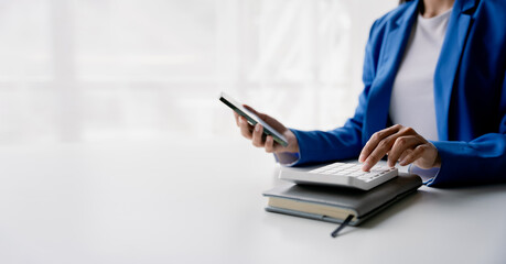Wall Mural - portrait of woman working in finance using smartphone and calculator in modern office, preparing acc