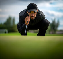"A Golfer Showcases Unwavering Precision And Concentration As They Line Up A Challenging Putt On A Green With A Steep Incline, A Testament To The Artistry And Skill Of The Sport."