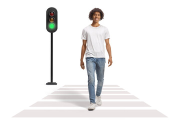 Wall Mural - Full length portrait of an african american guy smiling and walking at pedestrian crossing