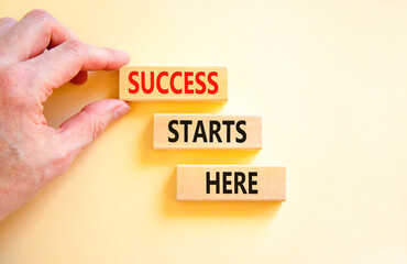 Wall Mural - Success starts here symbol. Concept word Success starts here on beautiful wooden block. Businessman hand. Beautiful white background. Business motivational success starts here concept. Copy space.