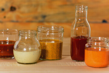 Handmade spicy sauces in glass jars on a colored wooden base - Salsas picantes hechas artesanalmente en frascos de vidrio sobre fondo de madera de colores