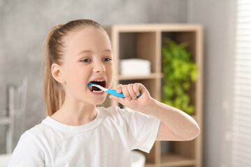 Wall Mural - Cute little girl brushing her teeth with plastic toothbrush in bathroom, space for text