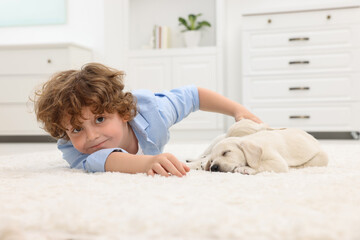 Canvas Print - Little boy lying with cute puppies on white carpet at home