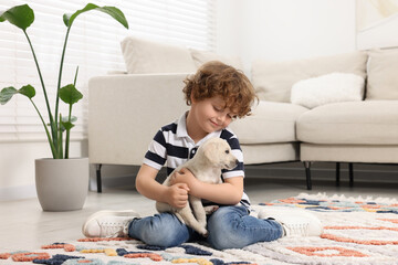 Canvas Print - Little boy with cute puppy on carpet at home