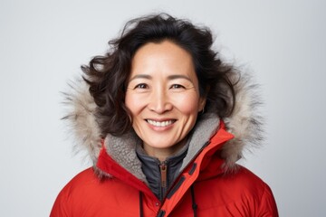 Wall Mural - Lifestyle portrait photography of a Vietnamese woman in her 40s wearing a warm parka against a white background