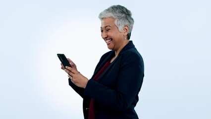 Canvas Print - Happy, laugh and senior business woman with phone in studio for funny, text or chat on blue background. Smartphone, app and elderly female ceo with online comic, social media or gif communication