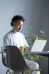 A man working at a computer in a white room. Image of engineers, freelancers, etc.