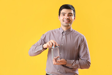 Canvas Print - Young man with bottle of water on yellow background