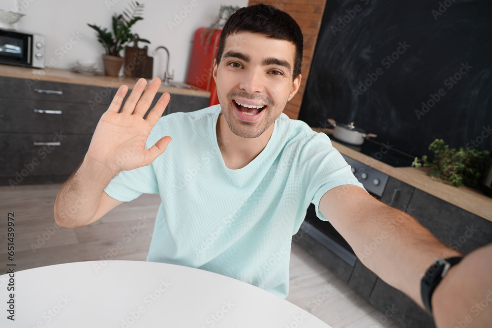 Young man video chatting in kitchen