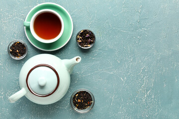 Wall Mural - Teapot, different types of tea and cup of beverage on color background