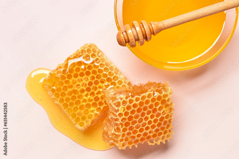 Glass bowl with sweet honey and combs on pink background