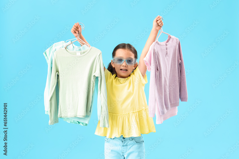 Cute little girl with new clothes on light blue background
