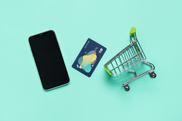 Sticker - Shopping cart with mobile phone and credit card on turquoise background