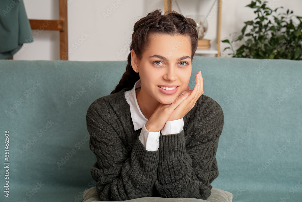Young brunette woman with pillow sitting on sofa at home