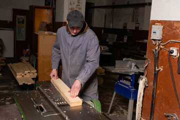 Wall Mural - A craftsman works on woodworking machines and saws in a furniture workshop