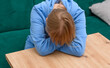 Załamana nastolatka z głową ukrytą w rękach, siedzi przy stole i płacze 