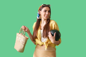 Wall Mural - Young woman with fresh watermelon and bag on green background