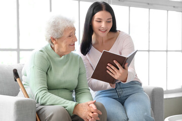 Canvas Print - Senior woman and her daughter with book at home