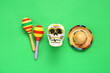 Leinwandbild Motiv Mexican maracas with painted skull and sombrero hat for Independence Day on green background