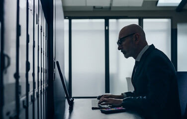 Fototapete - Silhouette of a middle-aged engineer working in a server room.