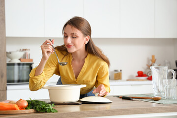 Young woman with chicken soup in kitchen