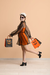 Poster - Young woman dressed for Halloween with gift bags near beige wall