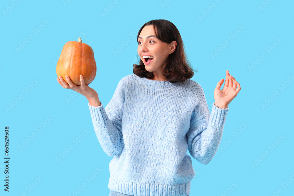 Young woman with pumpkin on blue background
