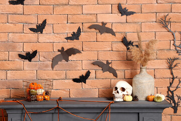 Mantelpiece with Halloween decor and paper bats on brick wall in room