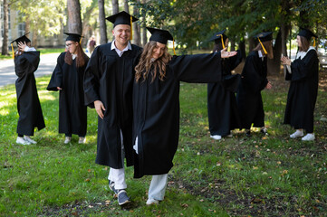 Wall Mural - A group of graduates in robes congratulate each other on their graduation outdoors.