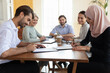 © fizkes - Satisfied diverse business people sitting at desk, middle eastern ethnicity and european company leaders signing contract legal document, make commercial profitable deal, negotiations activity concept