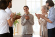 © fizkes - Best employee of month promoted successful female worker or newcomer receiving appreciation or encouragement from diverse staff clap hands her while she folded arms over chest feels flattered grateful