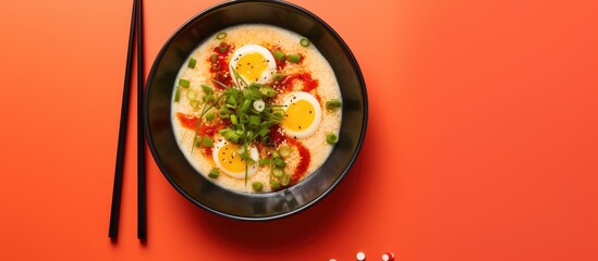 Wall Mural - Japanese style tofu with tobiko egg and spring onions served in a red and black bowl with soy sauce captured in top down view on a isolated pastel background Copy space