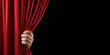 Hand open the red stage curtain. Isolated on black with copy space for text