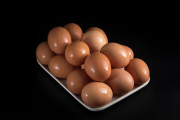 Wall Mural - tray with raw brown eggs, placed on a black background