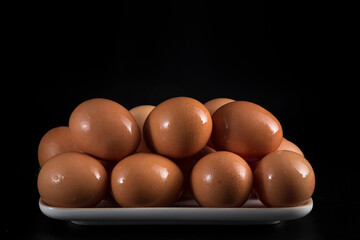 Wall Mural - tray with raw brown eggs, placed on a black background