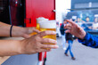 Zwei Hände reichen einer Person Bier in Plastikbechern