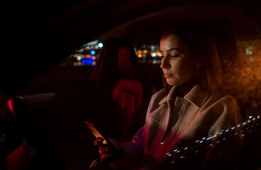 Beautiful businesswoman commuting from office in luxury car at night