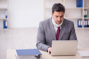 Wall Mural - Young male employee after car accident sitting in the office