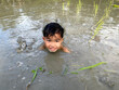 Thailand Asia boy is enjoy playing in the mud of rice field. Outdoor kid learning activity.